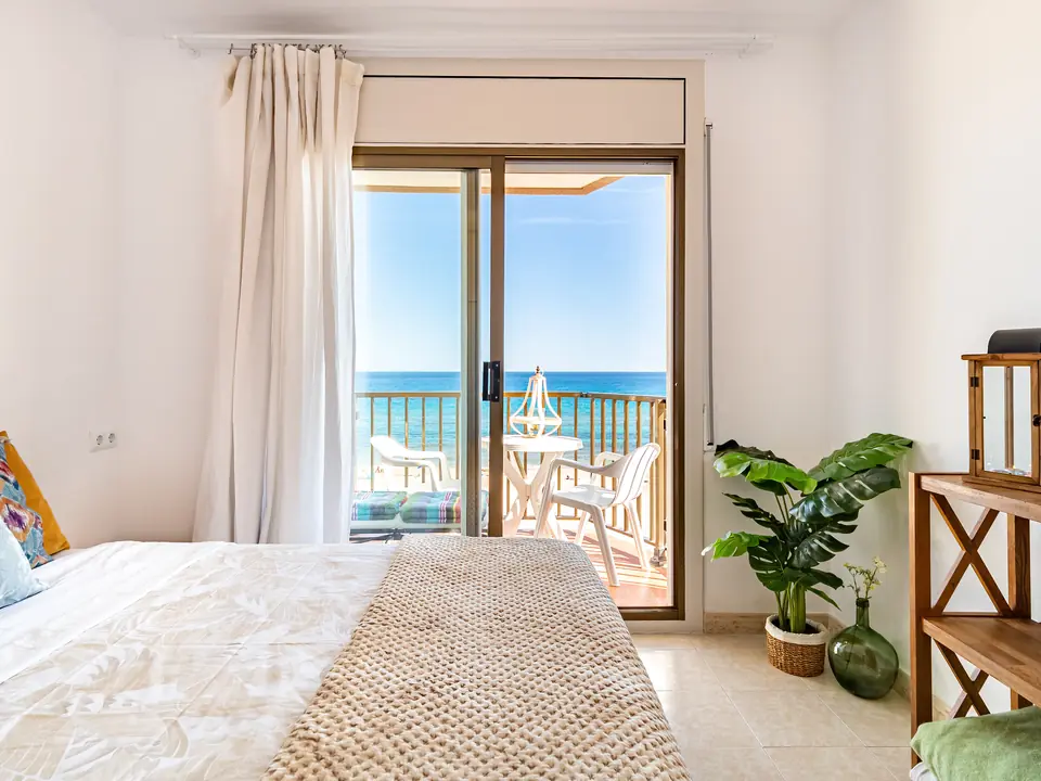 La camera La Terrazza: letto matrimoniale e la porta-finestra aperta sul terrazzino, col mare in fondo